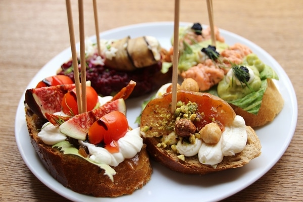 side view of 4 open-faced sandwiches with wooden skewers stuck in them