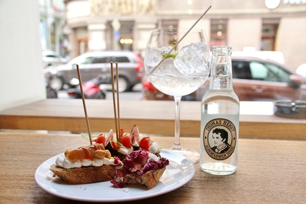 A plate of food and a bottle of seltzer on a table overlooking the street