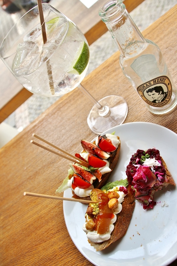 overhead view of a plate of sandwiches and a cocktail on a wooden surface