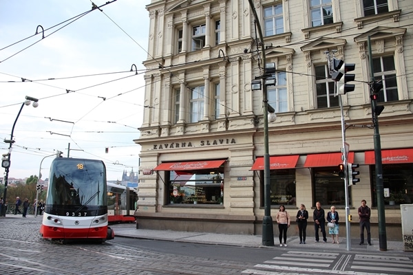 a tram driving by a corner building