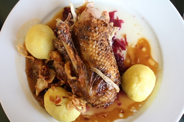 a plate of duck surrounded by potato dumplings