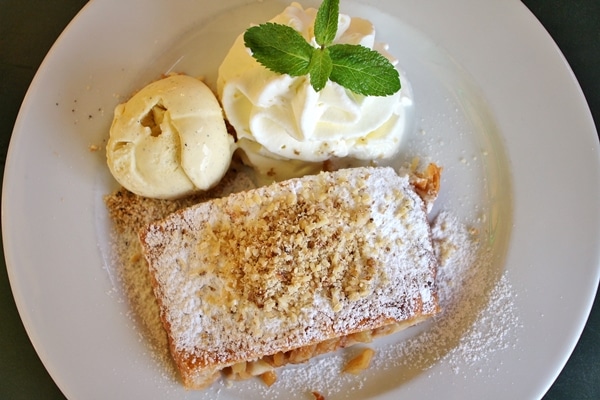 overhead view of a plate of apple strudel with ice cream and whipped cream
