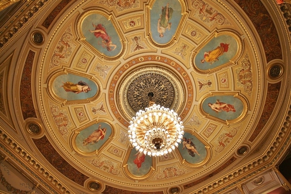 an ornate ceiling in a theater with a glass chandelier