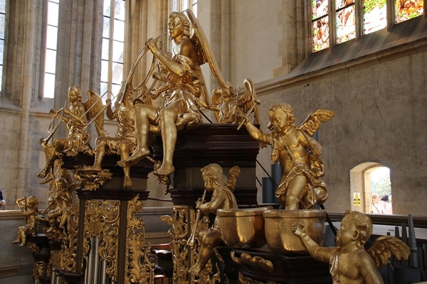 closeup of a church organ with gold figures on top