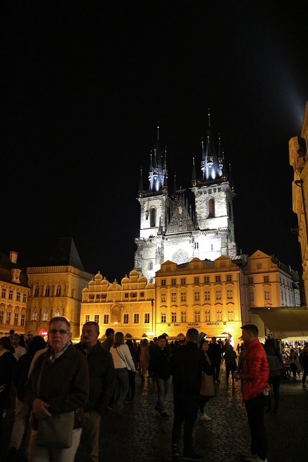 a group of people in a square at night in front of a large church