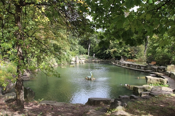 A small seal sculpture in a pond surrounded by trees