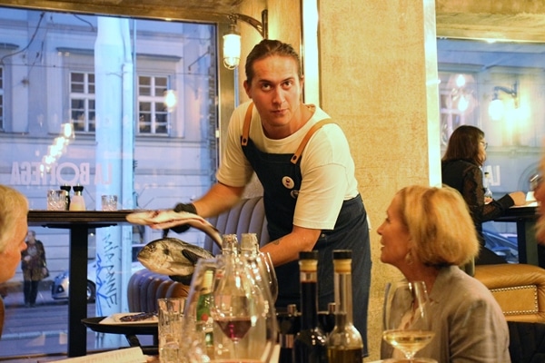 restaurant server holding up 2 fishes