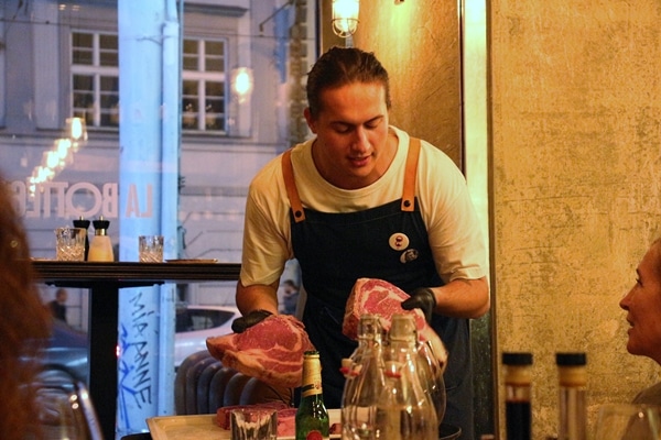 A man holding 2 large cuts of beef