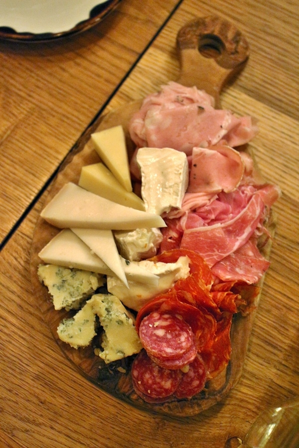 a variety of cured meats and cheeses on a wooden board