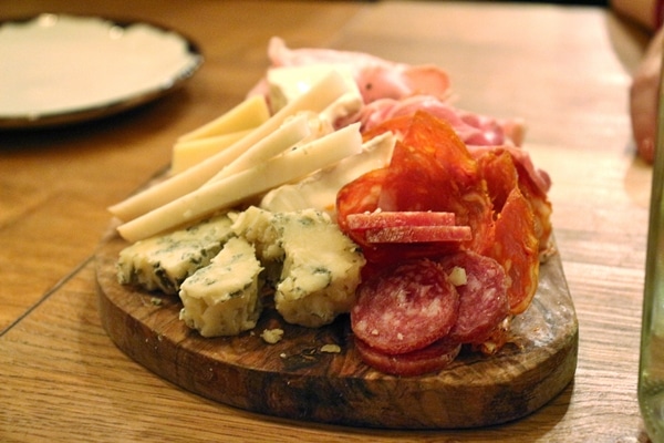 closeup of cured meats and cheeses on a wooden board