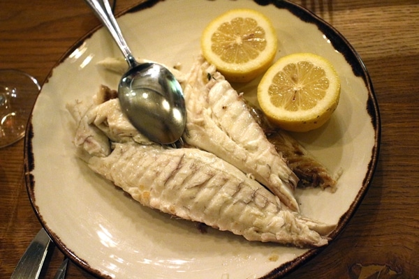 a fish fillet with lemon halves on a plate