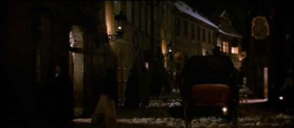 a screenshot from the movie Amadeus of a carriage going down a street at night