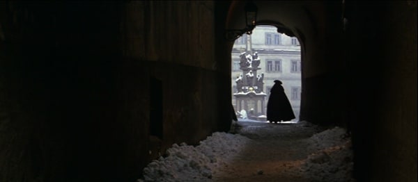 screenshot from the movie Amadeus of a cloaked man walking down a snowy tunnel