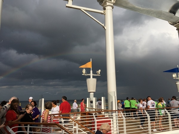 a rainbow in front of storm clouds as seen from cruise ship pool deck