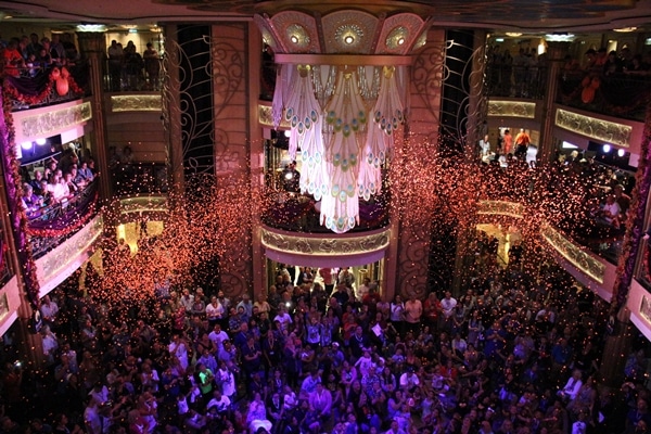 A crowd of people in the Disney Fantasy lobby atrium with confetti falling down