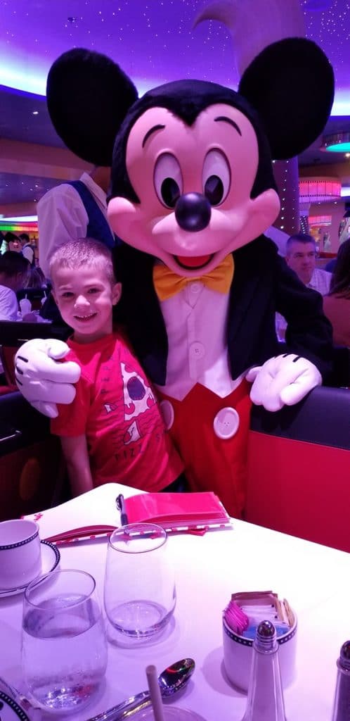 a boy posing with Mickey Mouse