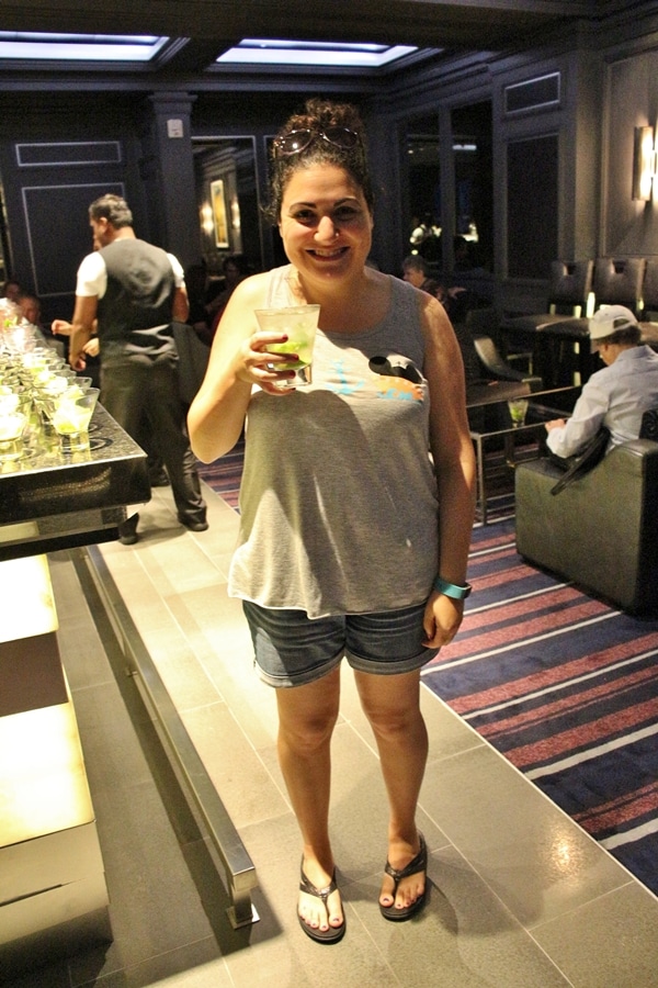 a woman holding up a mojito at a bar