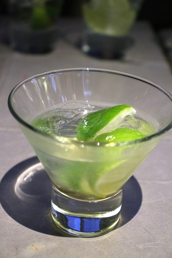 A close up of a cocktail with lime wedges