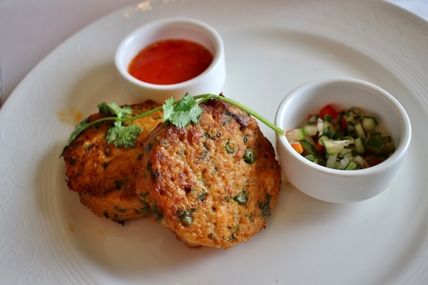 Thai fish cakes with red sauce on a white plate