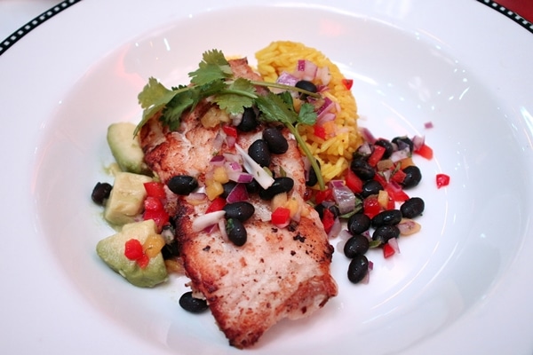 fish with black beans, vegetables, and rice on a plate