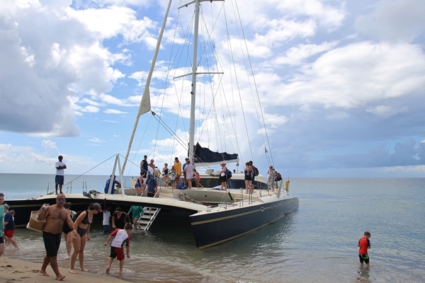 A group of people in a catamaran on the shore of a beach