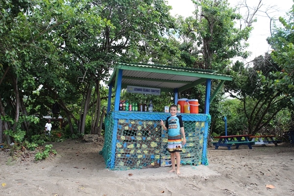 a boy giving a thumbs up on a shady beach