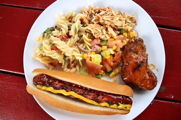 A plate of food with a hot dog and pasta salad