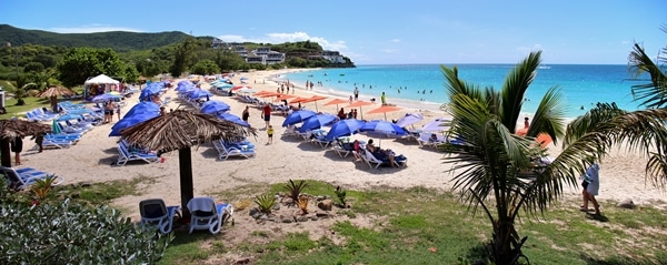 beach chairs with colorful umbrellas on a beach with turquoise waters