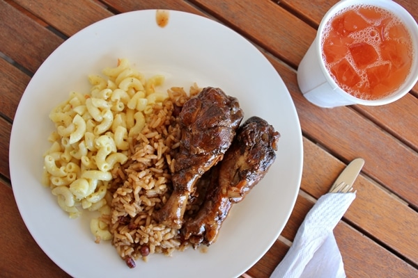 A plate of chicken, rice, and macaroni salad on a wooden table