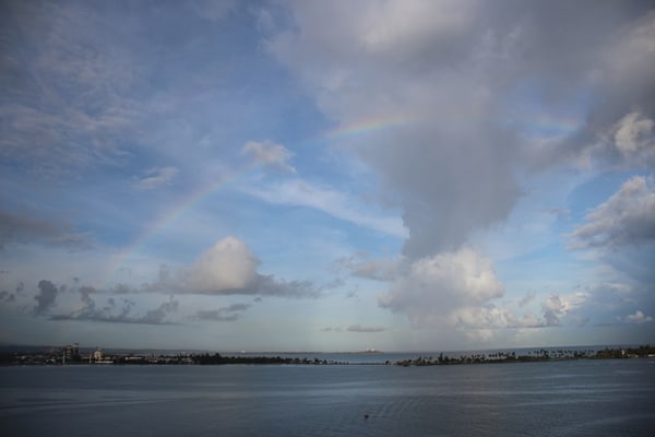 A group of clouds in the sky with a rainbow overhead