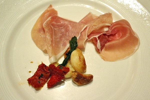 a plate of prosciutto with roasted garlic