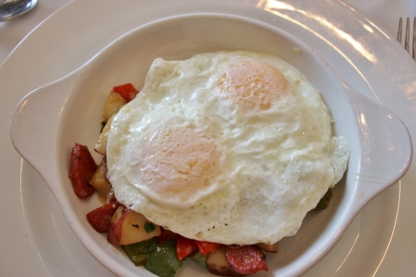 hash topped with fried eggs on a white plate