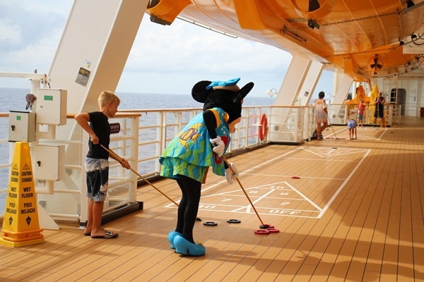 Minnie Mouse playing shuffleboard with a young boy on a cruise ship