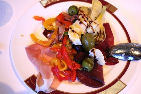 an antipasti plate with cured meats, cheeses, olives, and vegetables