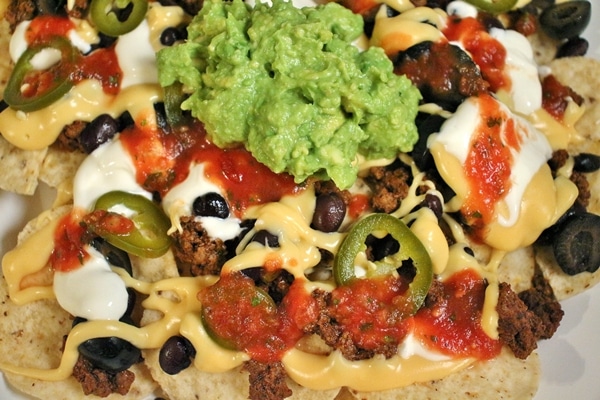 Nachos with Taco Meat, Nacho Cheese Sauce, Guacamole, Salsa, Olives, Beans, Pickled Jalapenos, Sour Cream, and Tortilla Chips