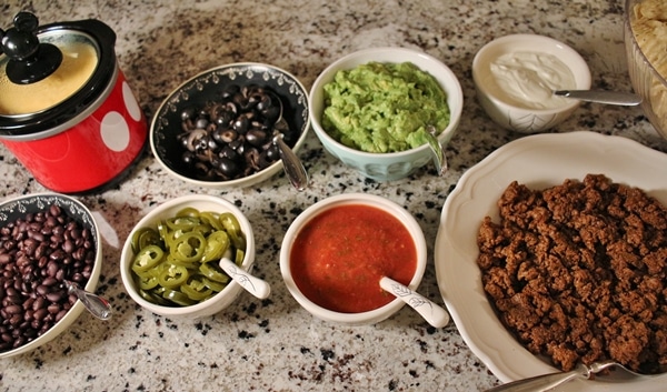 Nacho Bar with Taco Meat, Nacho Cheese Sauce, Guacamole, Salsa, Olives, Beans, Pickled Jalapenos, Sour Cream, and Tortilla Chips