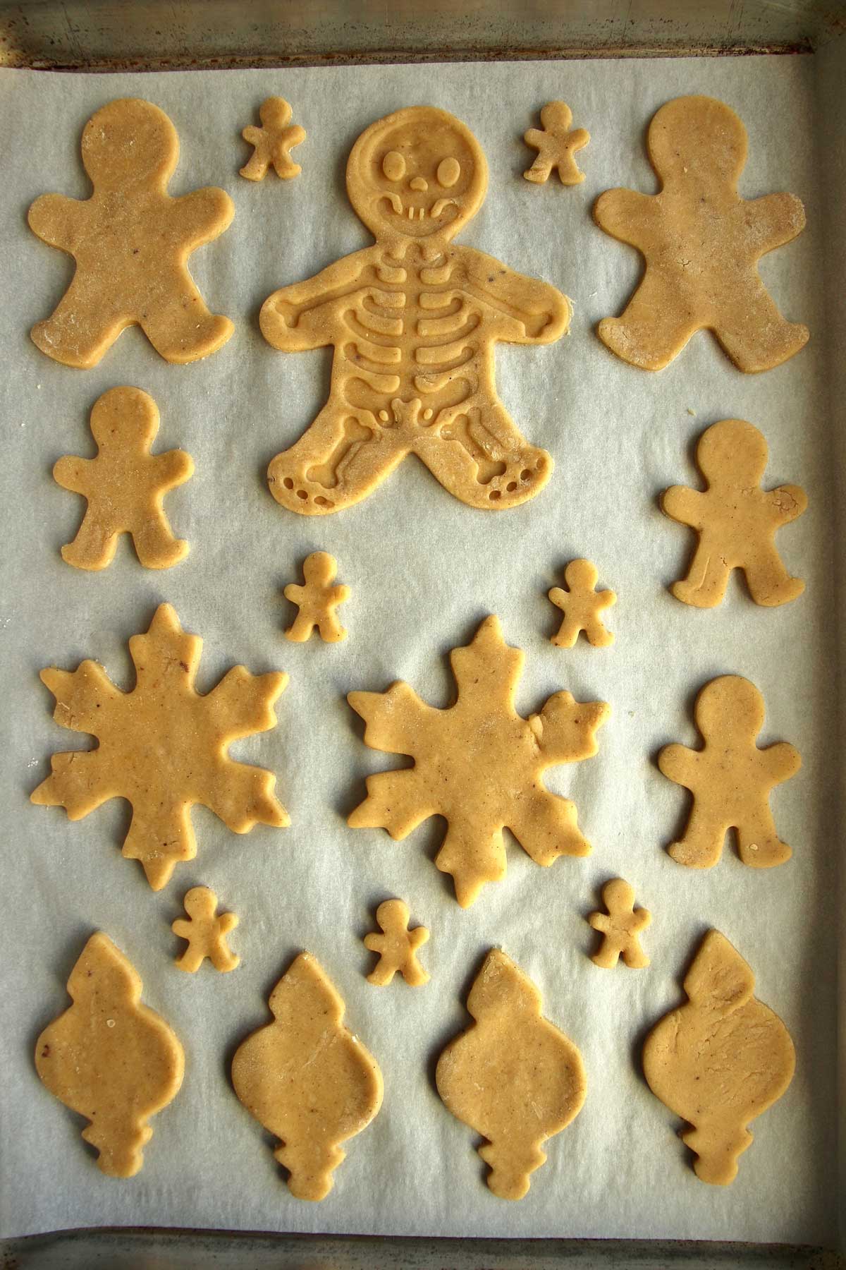 A baking sheet topped with unbaked Czech gingerbread cookies in various shapes.