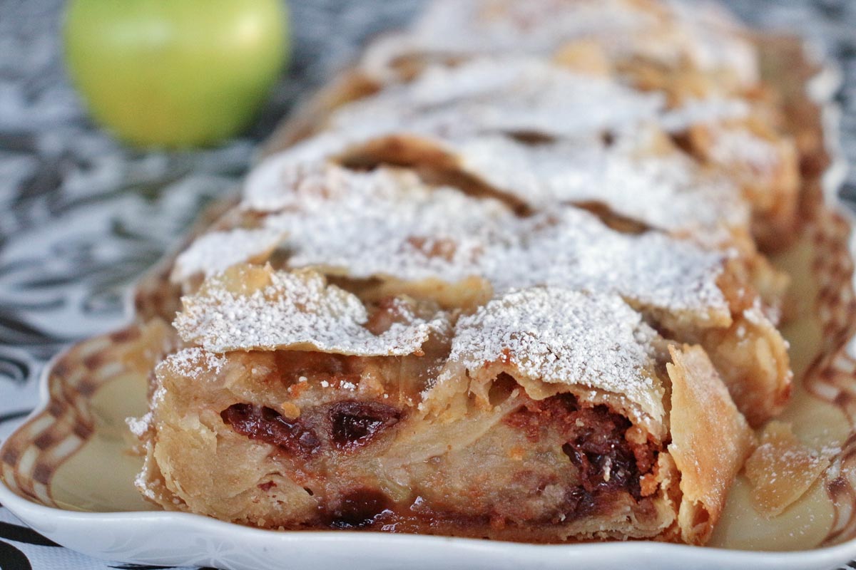 A platter of apple strudel and a green apple in the background.