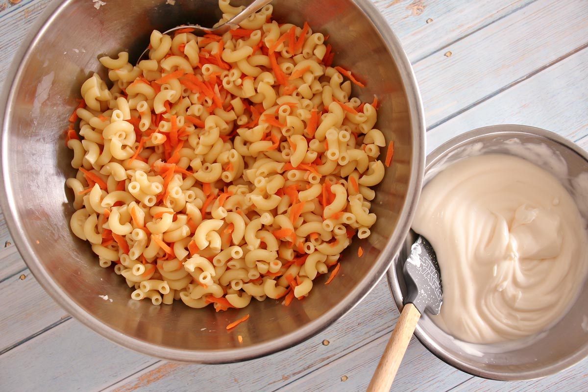 Metal mixing bowl with elbow macaroni, small metal mixing bowl with mayonnaise-based dressing.