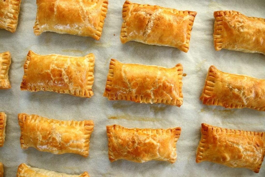 Rectangular golden puff pastry meat boreks on a baking sheet