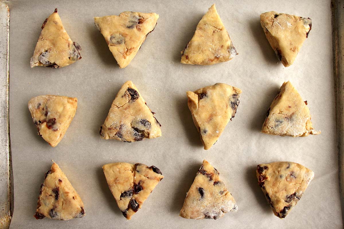 Unbaked triangular scones arranged on a baking sheet.