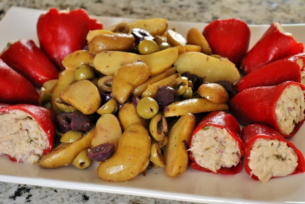 A platter of tuna-stuffed piquillo peppers on either end, and potato and olive salad in the middle