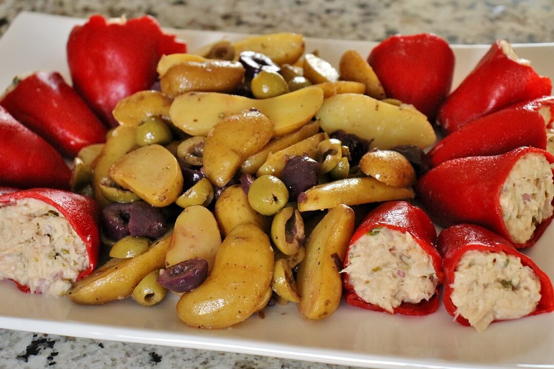 A platter of tuna-stuffed piquillo peppers on either end, and potato and olive salad in the middle