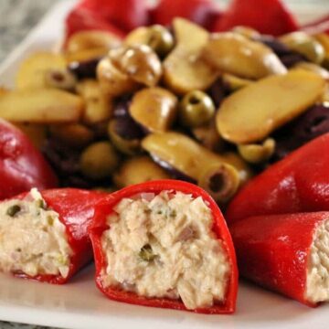 Tuna-stuffed piquillo peppers on a platter with fingerling potato and olive salad