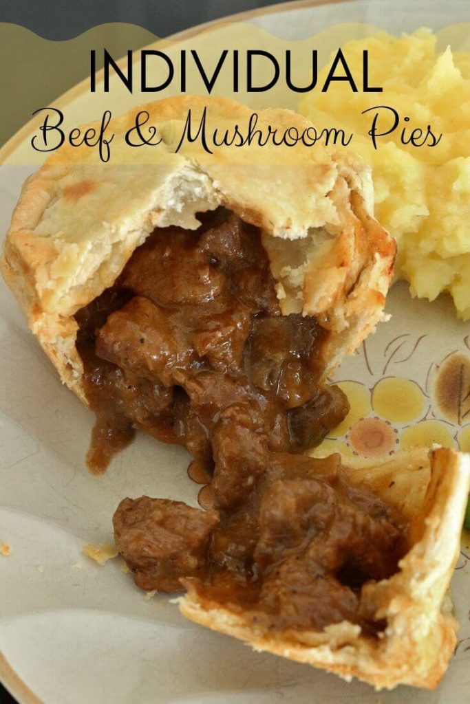 Individual beef and mushroom pie cut open with the filling pouring out, with mashed potatoes and peas on the side.