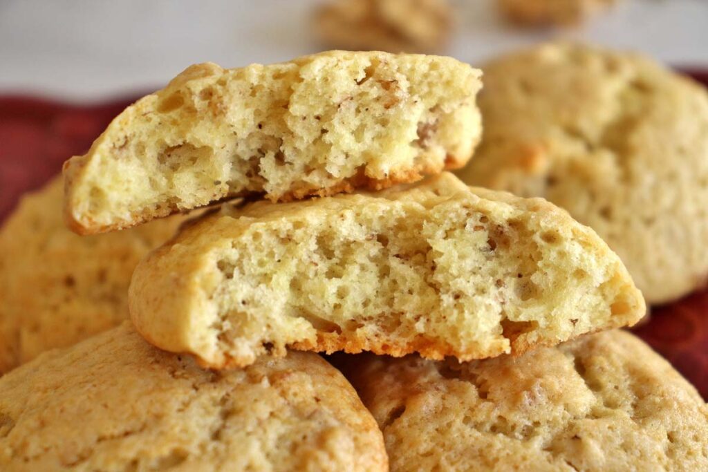 Close up of a plate of fluffy yogurt cookies with one broken in half to show the interior