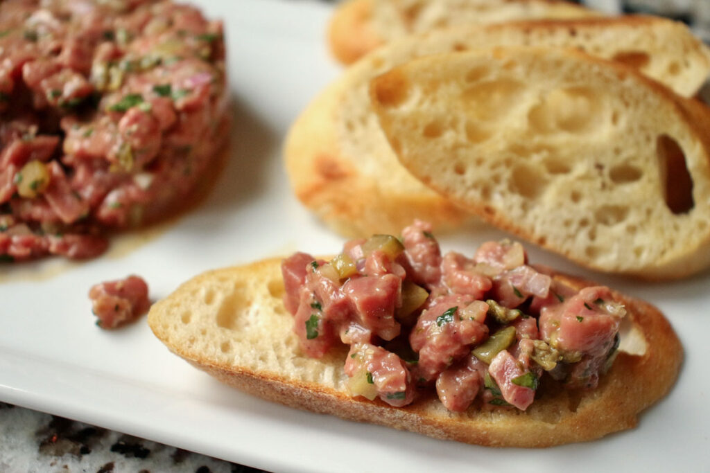 Closeup of a baguette slice topped with beef tartare