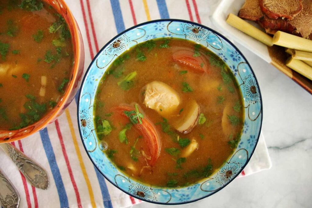 Colorful, floral bowls filled with Thai hot and sour soup with chicken