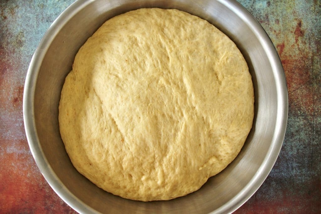 Chorek dough in a large metal mixing bowl after proofing, doubled in size