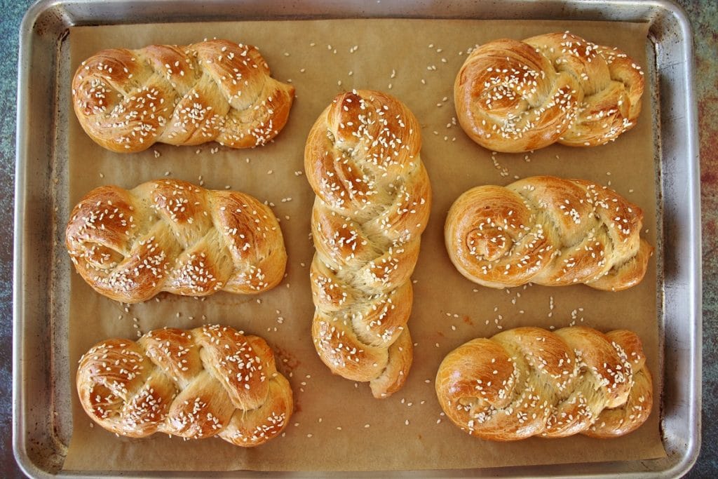 A sheet pan of braided baked choreks topped with sesame seeds